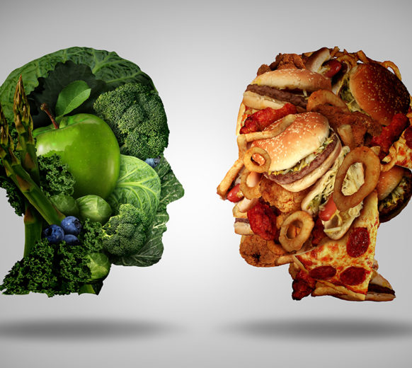 Lifestyle choice and dilemma concept as a two human faces one made of fresh green vegetables and fruit and the other head shaped with greasy fast food as hamburgers and fried foods as a symbol of nutrition facts and healthy living issues.